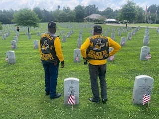 Two Buffalo Soldiers members standing among headstones at veterans cemetery